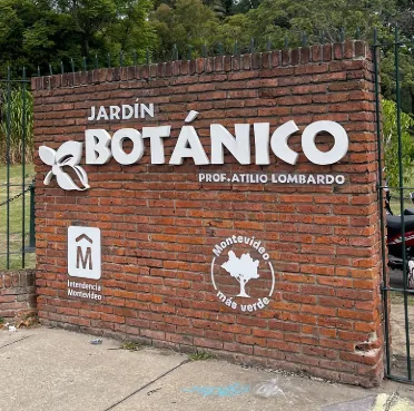 Muro de ladrillo en el acceso con el cartel «Jardín Botánico Prof. Atilio Lombardo»